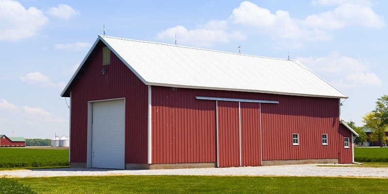 Red steel-frame event barn with white sliding doors and standing-seam roof — an event barn configuration.