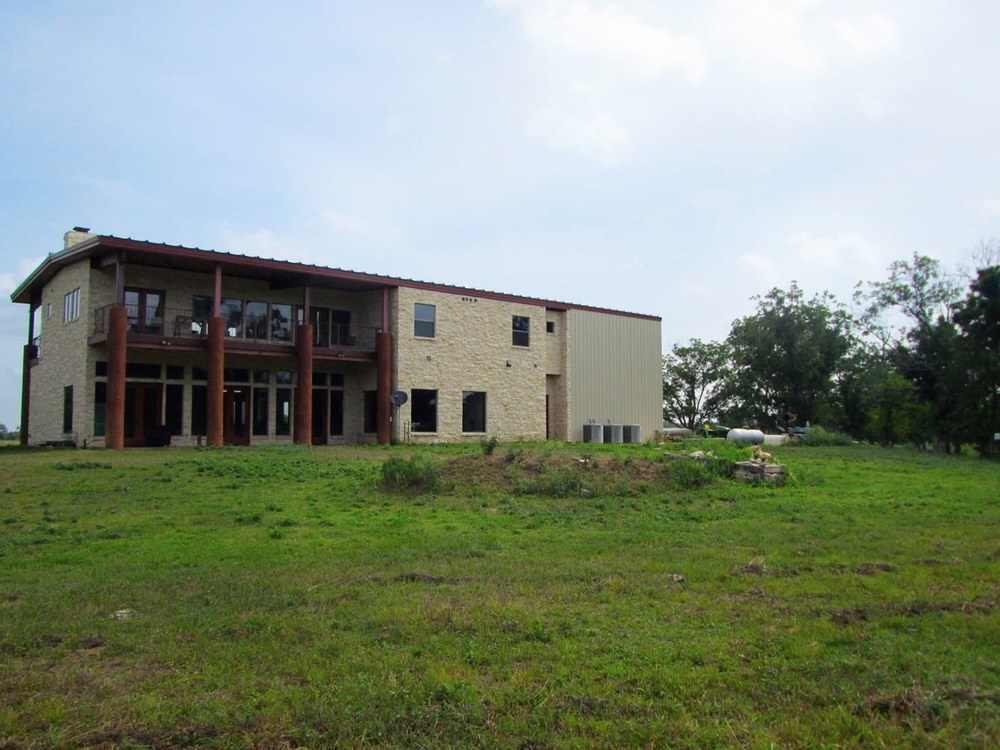 A traditional-footprint red-iron steel-frame home with stone exterior and standing-seam roof — a the manufacturer residential configuration.